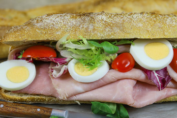 sandwich au jambon et crudités sur une planche à découper