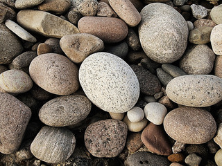 Fototapeta na wymiar A natural texture made of big grey granite stones pebbles from Baltic sea beach. 