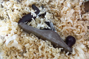 An old fashioned wood plane lies amongst the wood shavings it created.