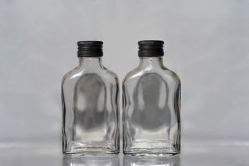 Two empty  russian vodka glass bottles with black  caps on a grey background horisontal image