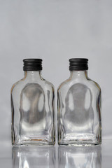 Two empty  russian vodka glass bottles with black  caps on a grey background vertical image