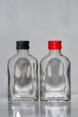 Two empty  russian vodka glass bottles with black and red caps on a grey background vertical image