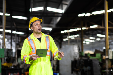 Portrait Engineer man working with computer laptop or tablet at factory Equipment. Chief Engineer in the Hard Hat Holds Laptop at the industrial facility.