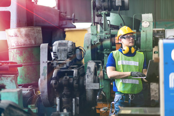 Portrait Engineer man working with computer laptop or tablet at factory Equipment. Chief Engineer in the Hard Hat Holds Laptop at the industrial facility.
