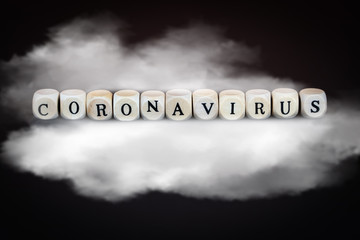 The word coronavirus in wooden cubes on a cloud, black background