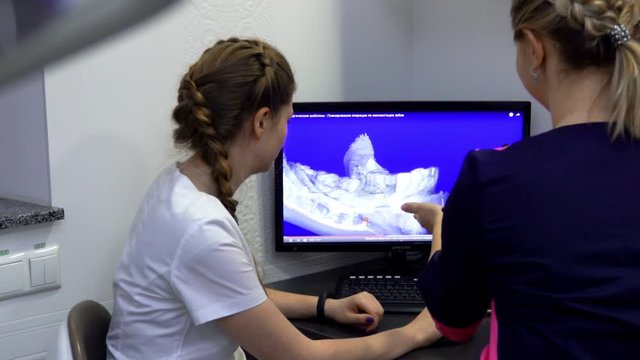 Dentist and the patient looking at the 3D image of the jaw at the monitor and deciding which teeth should be cured