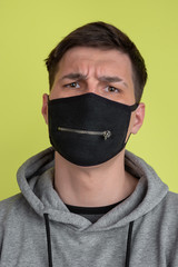 Asking. Close up caucasian man's portrait isolated on yellow studio background. Freaky male model in black face mask. Concept of human emotions, facial expression, sales, ad. Unusual appearance.