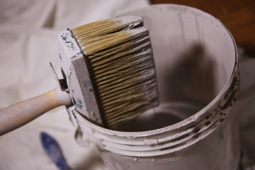 Pennellessa e secchio di vernice; strumenti da imbianchino per tinteggiare. Primo piano 