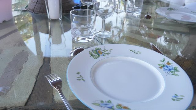 Close up circle pan of a white place setting on a glass table