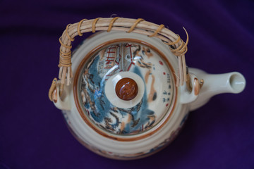 Top view of traditional ceramic chinese teapot standing on dark violet background