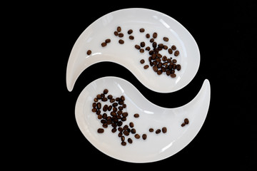 Two white plates with black coffee beans on black background, top view