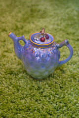 Closeup view of colorful ceramic vintage teapot standing on green carpet
