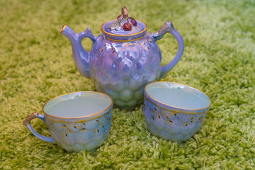 Closeup view of colorful ceramic vintage tea set standing on green carpet