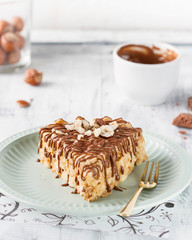 A piece of cake with nuts, poured with chocolate, lies on a blue plate.