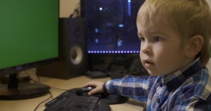 Little Child Learning How to Use Computer Mouse Surfing Internet Playing Watching PC. Boy Sits in Front of Green Screen Monitors. Father's Editing PC Workstation. Gaming PC. 10 bit HLG