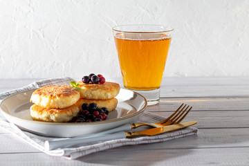 Homemade pancakes with cottage cheese on a white lantern with black currants and cranberries. Breakfast for the whole family. Healthy vegan food concept.