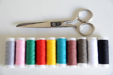 Accessories for tailoring on white table - Scissor , scissors, buttons, needle and thread, spools of colored threads