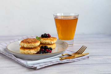 Homemade pancakes with cottage cheese on a white lantern with black currants and cranberries. Breakfast for the whole family. Healthy vegan food concept.