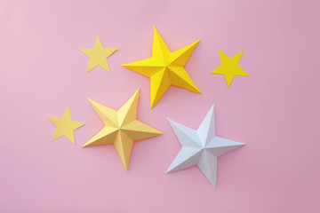 Handmade paper art and cut white and yellow stars on pink background. 