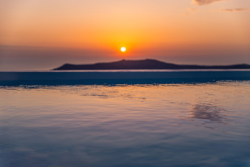 Amazing sunset relaxing mood the pool in a luxurious hotel resort at sunset enjoying perfect beach holiday vacation. Summer landscape, beautiful sunset sky, banner concept of Santorini vacation