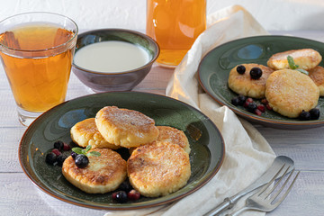 Homemade pancakes with cottage cheese on a white lantern with black currants and cranberries. Breakfast for the whole family. Healthy vegan food concept.
