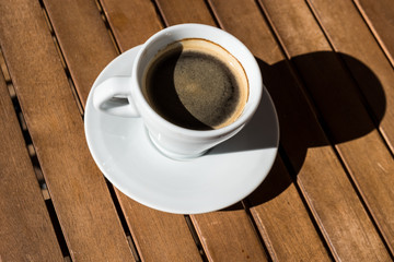Cup of coffee on wooden table, top view