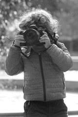 Fototapeta premium Child learns to take pictures in a park with a professional reflex camera