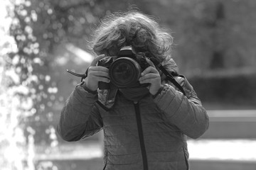 Fototapeta premium Child learns to take pictures in a park with a professional reflex camera