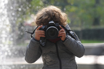 Fototapeta premium Child learns to take pictures in a park with a professional reflex camera