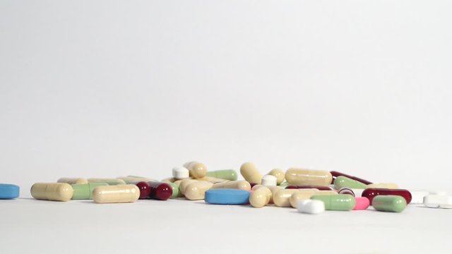 Pills and medicines falling in slow motion on white background. Cure and treatment against viruses and bacteria. Vitamin complex. Slow motion.