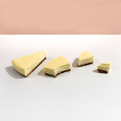 Bright pieces of cheesecake on white pink background