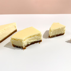 Bright pieces of cheesecake on white pink background