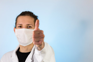 An adult male dressed in a white lab coat with a protective face mask on while giving a thumbs up. Ready to work in a clean room or laboratory