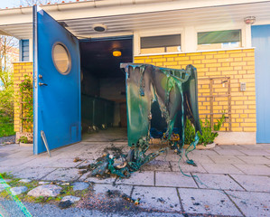 Green trash container melted by a single use barbeque.
