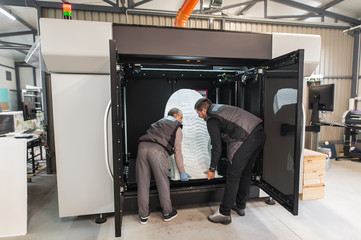 Technicians wear huge 3d model printed on large 3d printer