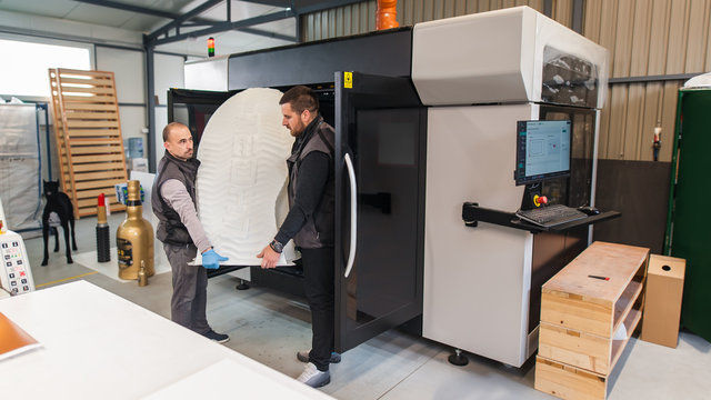Technicians wear huge 3d model printed on large 3d printer