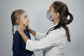 Female doctor examining touching neck check throat lymph gland tonsils of cute child. Female caucasian doctor is palpating lymph node on the neck of 5 years old girl