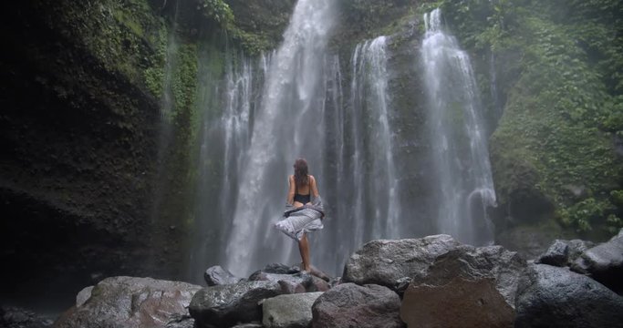 picturesque scenery of shocking wildlife back view of slim girl posing at mountain waterfall.