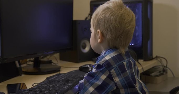 Serious Little Child Watching Cars Driving Racing Videos Games on Computer Monitor. Father's Editing PC Workstation. Gaming PC. 10 bit HLG