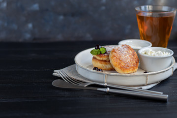 Homemade pancakes with cottage cheese on a dark lantern with black currants and cranberries. Breakfast for the whole family. Healthy vegan food concept.