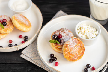 Homemade pancakes with cottage cheese on a dark lantern with black currants and cranberries. Breakfast for the whole family. Healthy vegan food concept.