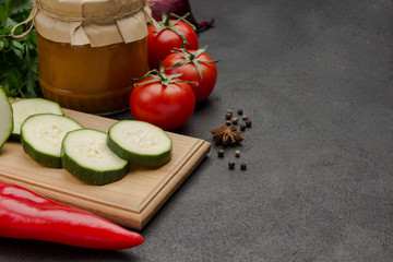 Fermented squash spread in glass jar. Raw vegetables and spices: carrots garlic, onions tomatoes, chili peppercorn.