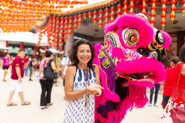 Fototapeta premium Chinese New Year celebration in a Chinese temple. A Chinese dragon dances and distributes sweets and tangerines. Festive Chinese entertainment