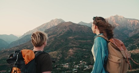 Young couple having an adventure, exploring beautiful mountains, hiking with backpacks, doing a fistbump - active lifestyle, freedom concept 4k footage