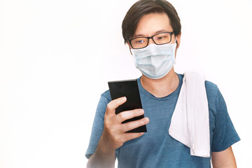 Portrait asian man wear glasses and mask to protect virus covid-19 and watch smartphone to unlock device on white background.