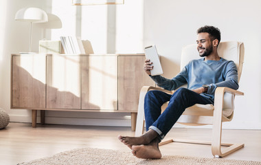Young man using digital tablet at home. Handsome student resting t in his room. Home work or study, freelance concept