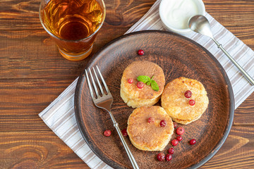 Homemade pancakes with cottage cheese on a wooden lantern with black currants and cranberries. Breakfast for the whole family. Healthy vegan food concept.