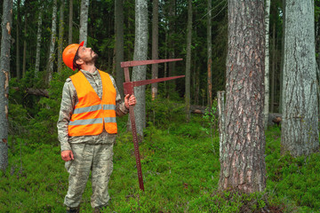 Forest worker performs taxation of forest stands. Forest officer in work clothes. Real people work. Forest certification.