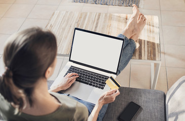 Young woman using laptop computer and holding credit card at home. Freelance, student lifestyle, distance education, technology and online shopping concept