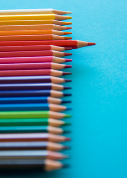 Set Of Colored Pencils On A Blue Background And The Red Colored Pencil Predominates